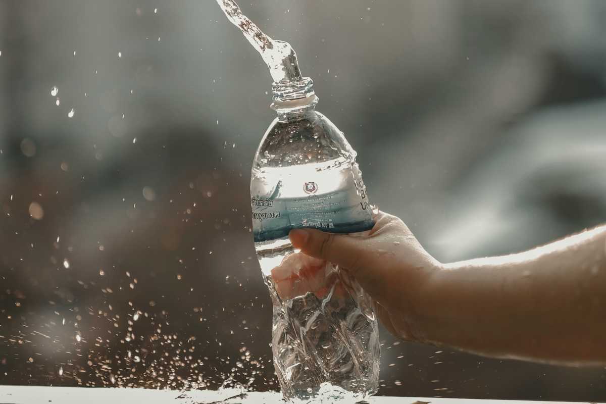 Persona che schiaccia bottiglia d'acqua